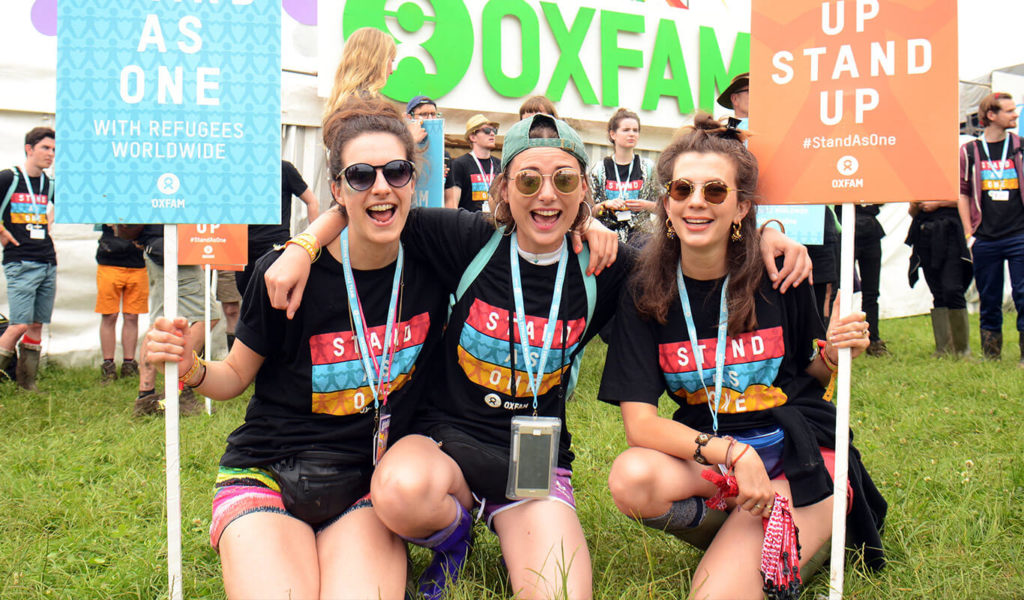 Oxfam campaigners holding Stand as One signs at Glastonbury festival. Photo credit: Marc West/Oxfam