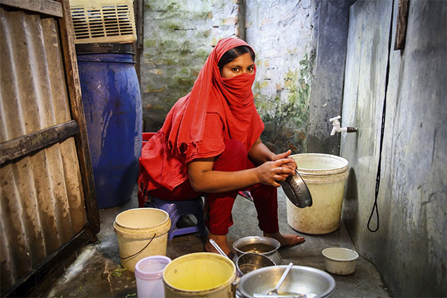 Forida sitting and washing utensils wearing red clothing