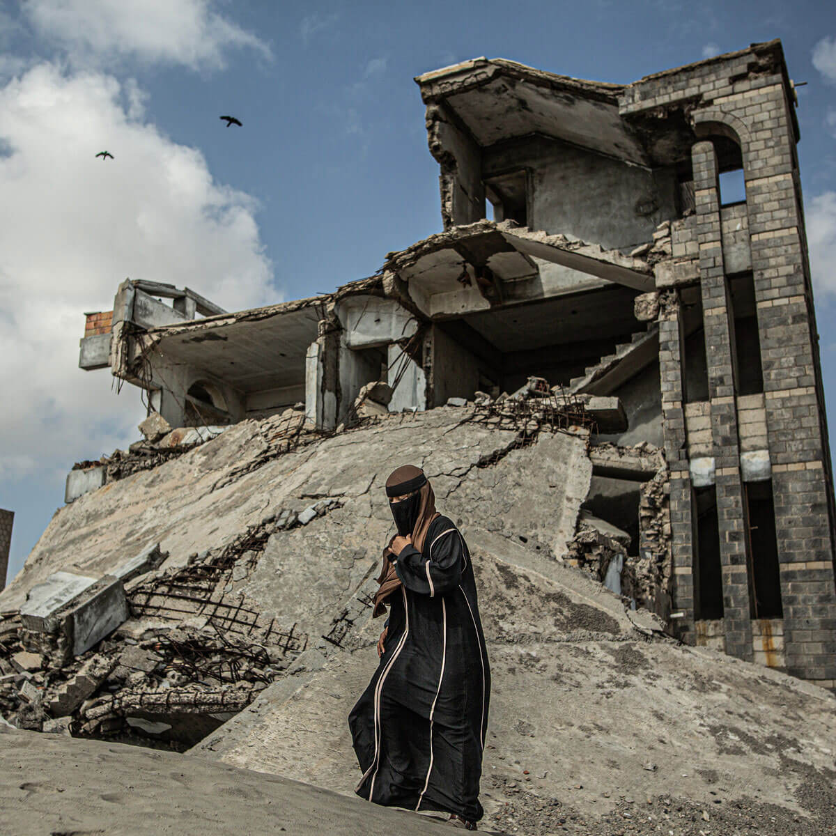 A woman walks near the ruins of a building