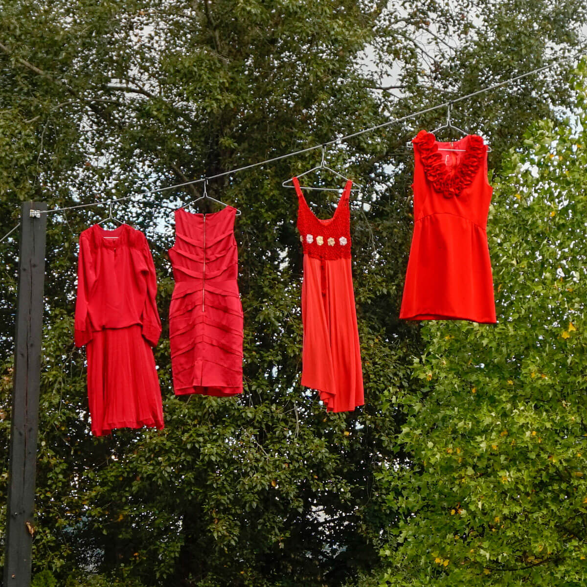 Four red dresses hanging on a clothesline