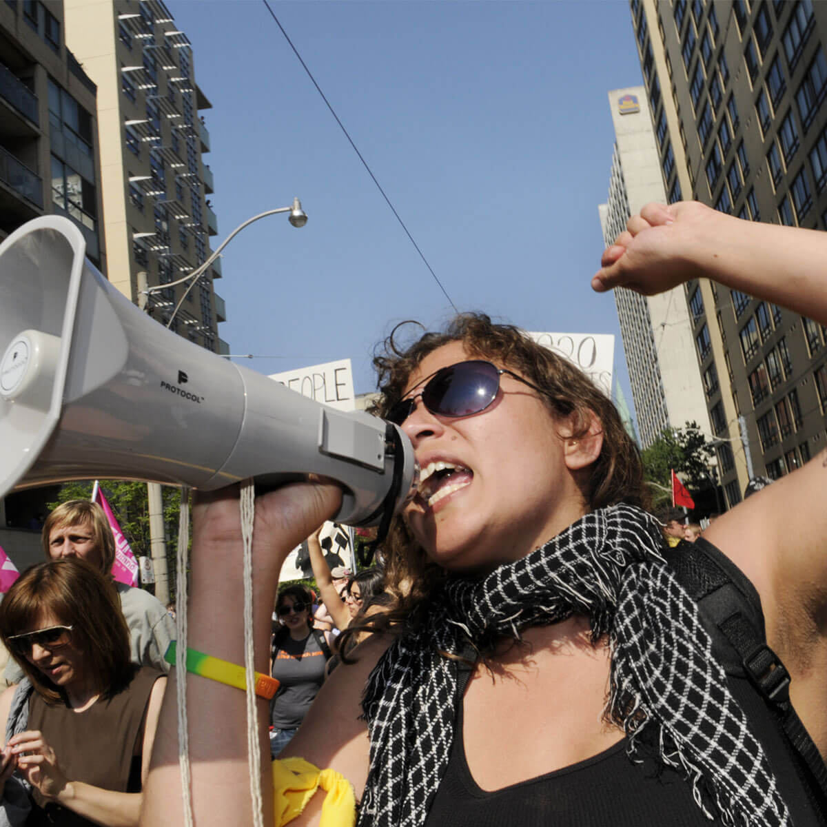 A woman speaking in a megaphone with her fist raised