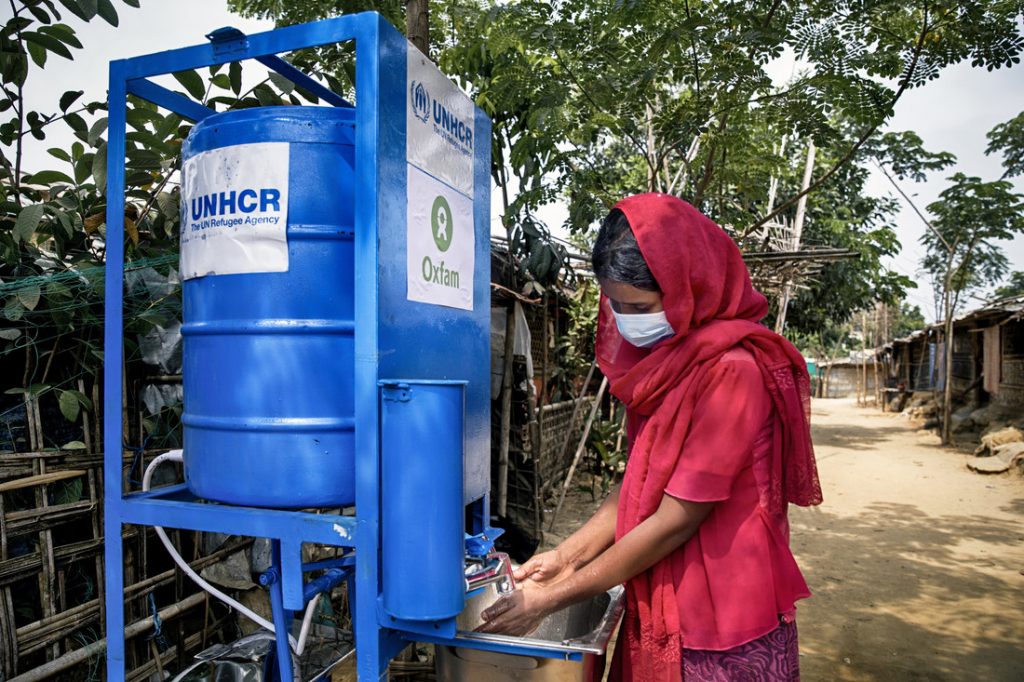Nur, a Rohingya refugee stands by an Oxfam handwashing station.