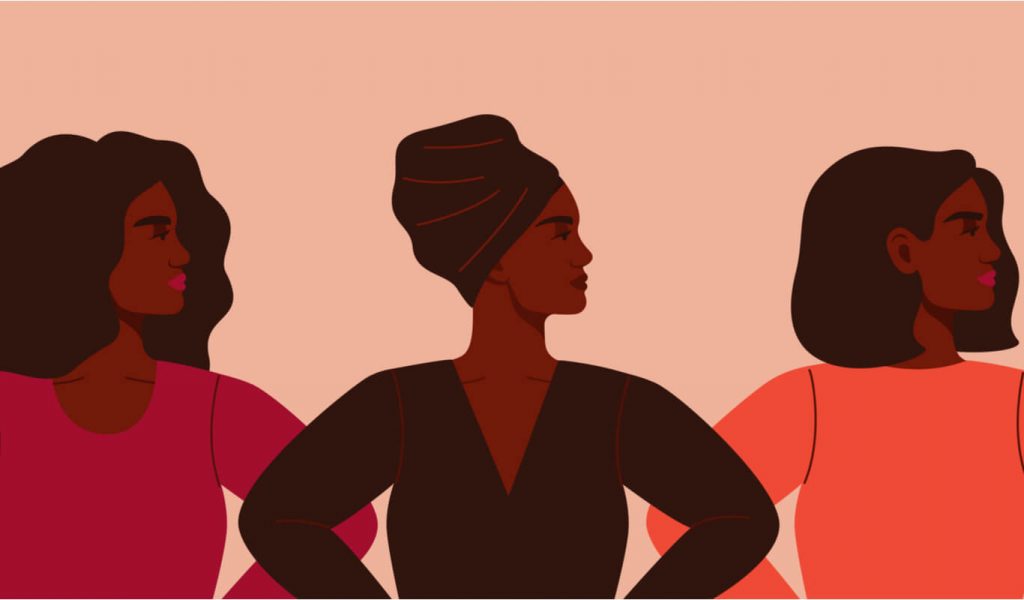 This is an illustration of three Black women standing next to each other. The woman on the left has a red long-sleeved shirt and long hair, the woman in the middle has her hair wrapped and is wearing a long-sleeved dark shirt and the woman on the right has short hair and is wearing a long-sleeved orange shirt. All of them are looking to the right with their hands on their hips and have serious looks on their faces.