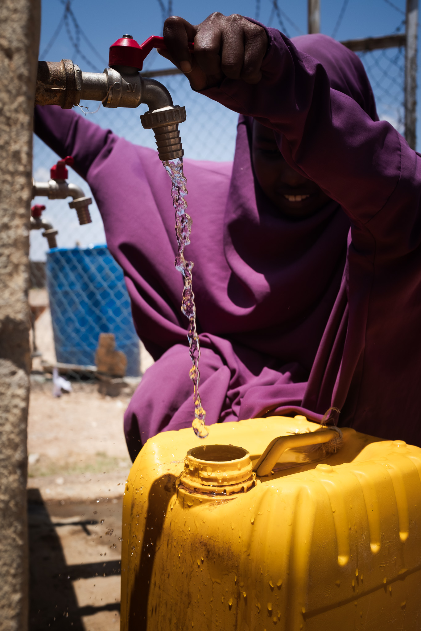 A young woman fetches clean water at an Oxfam distribution centre. Photo: Caroline Leal/Oxfam