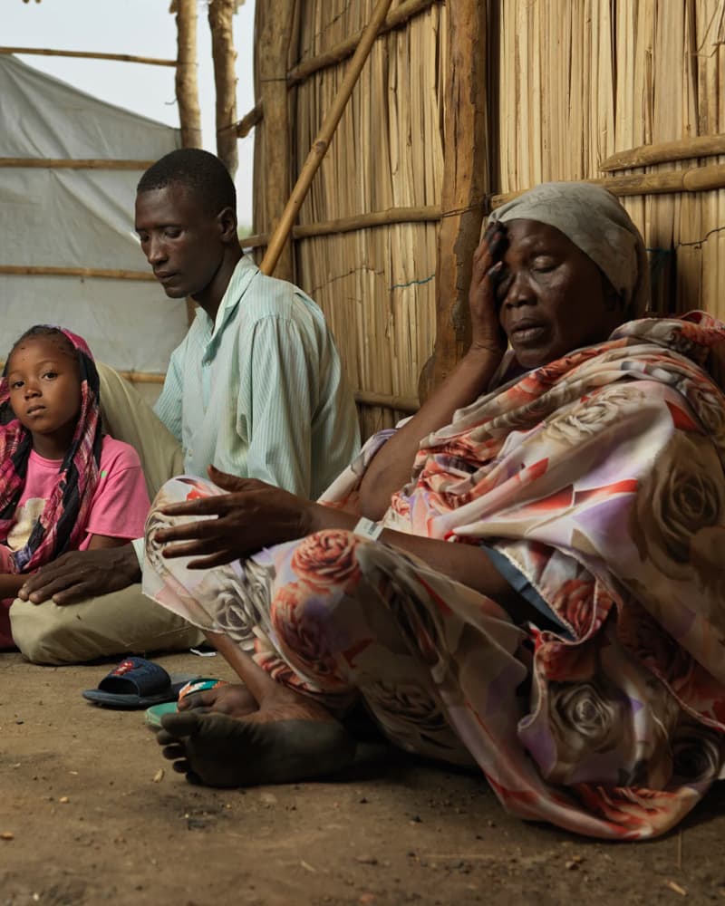 A young man and woman sitting on the floor of a wooden hut, closing their eyes with disappointed looks on their faces.