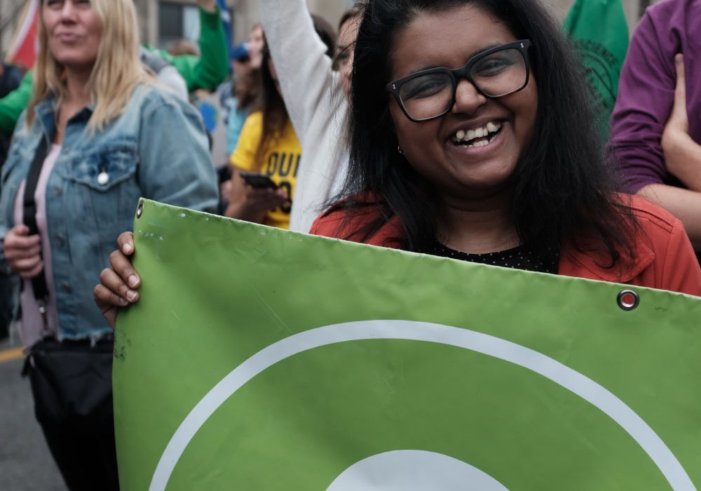 A woman holding an Oxfam Canada banner smiles for the camera.