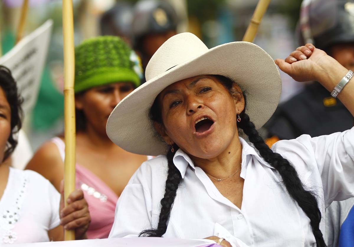 A woman wearing heat is seen talking while marching the streets in a protest.