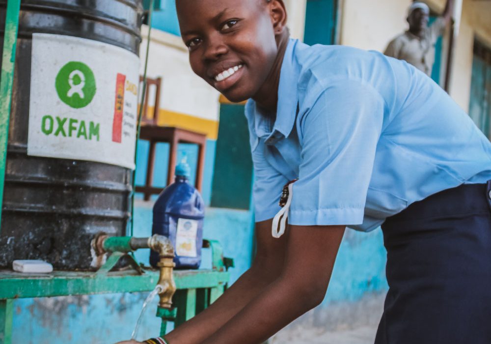 A young woman washes her hands at an Oxfam handwashing station.
