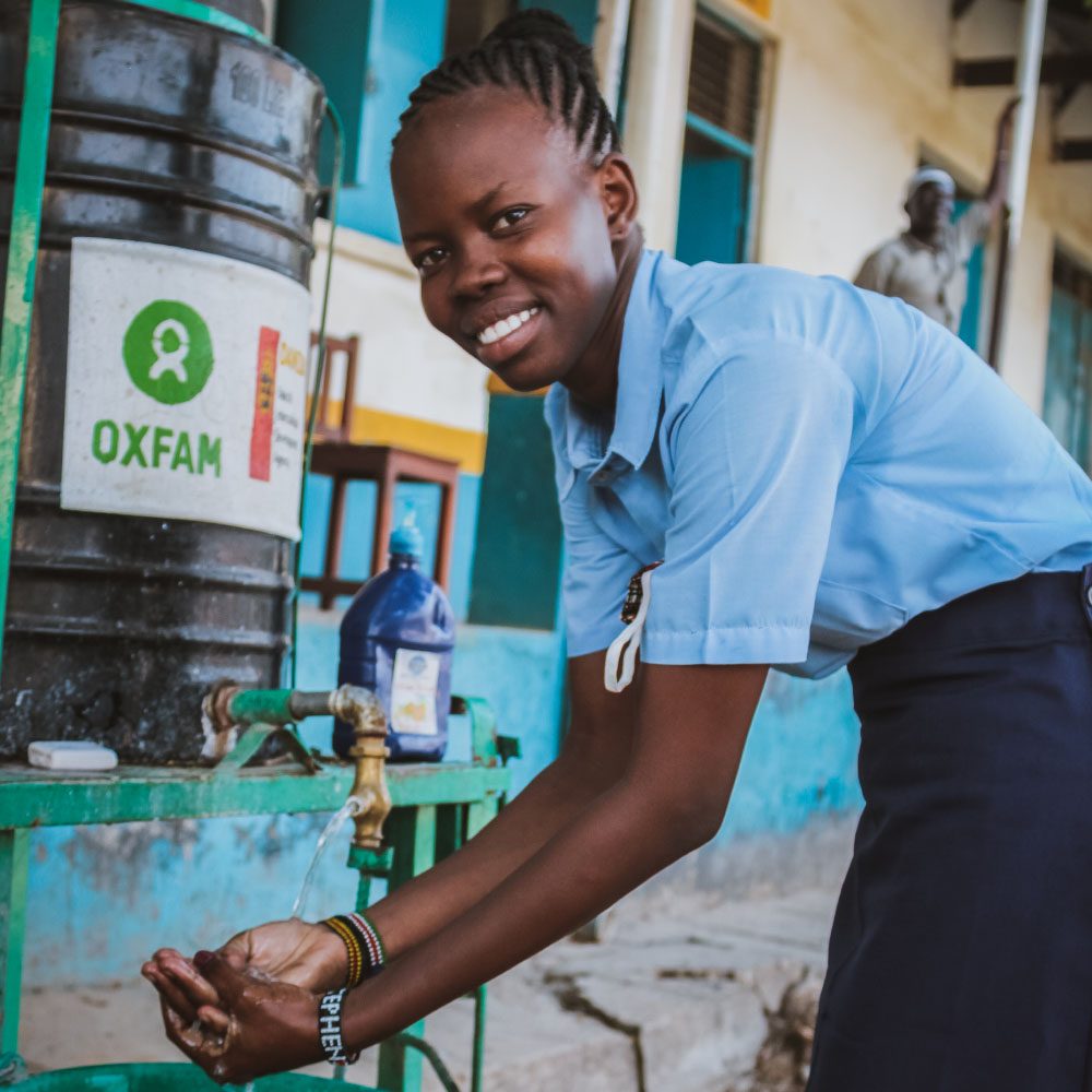 A young woman washes her hands at an Oxfam handwashing station.